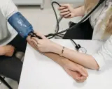 Lekarz mierzy ciśnienie krwi pacjentowi. Na ramieniu pacjenta założony jest mankiet, a lekarz obserwuje wskazania na ciśnieniomierzu, aby sprawdzić wynik w mmhg.