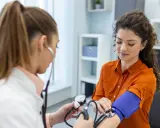 Lekarka mierzy ciśnienie pacjentce. Wynik 160 na 80 wskazuje na podwyższone ciśnienie.
