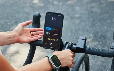 Rowerzysta sprawdza na telefonie, co oznacza puls 91. Na ekranie widać tętno 113 BPM i czas treningu.