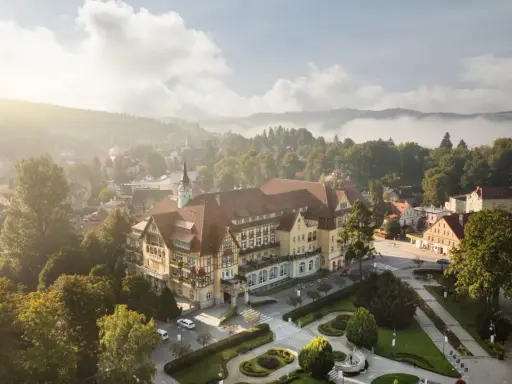 Sanatorium Polonia w Kudowie Zdroju, z pięknymi pokojami i otoczeniem, w mglisty poranek.