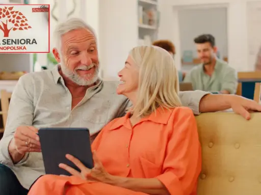 Uśmiechnięta para seniorów z tabletem, w tle logo "Karta Seniora Ogólnopolska".