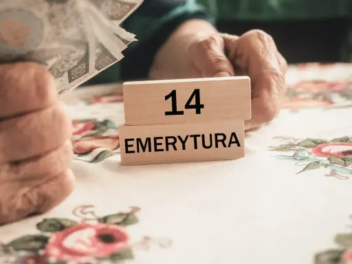 Dłoń trzyma banknoty, obok kostki z napisem "14 EMERYTURA". Zastanawiasz się, ile to brutto, gdy masz 2200 netto?