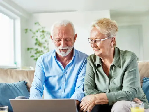 Uśmiechnięta para seniorów przegląda w internecie informacje, jak załatwiać sanatorium.
