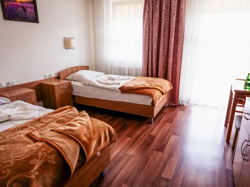 Pokój w sanatorium Busko-Zdrój, prywatnie Krystyna. Dwa łóżka, szafki nocne, stół z krzesłem i butelkami wody.