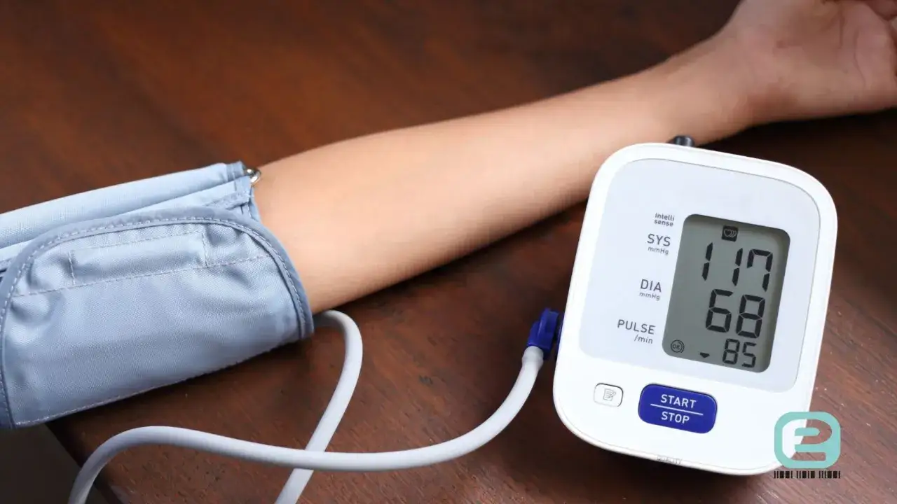 Ramię z mankietem ciśnieniomierza, na ekranie widoczne parametry ciśnienia: 117/68 mmHg i puls 85/min.